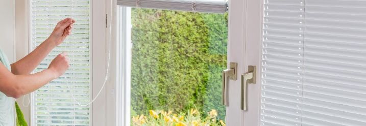 Person justiert Jalousie an Terrassentür